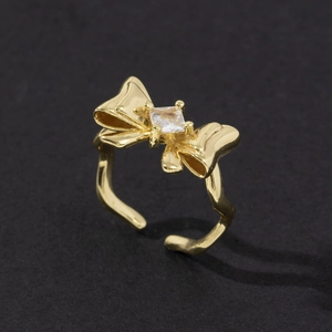 Gros plan détaillé d'une bague nœud dorée avec zircon carré et anneau texturé ondulé