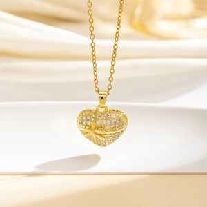Macro di un ciondolo a cuore dorato con zirconi brillanti e un dettaglio a fiocco raffinato