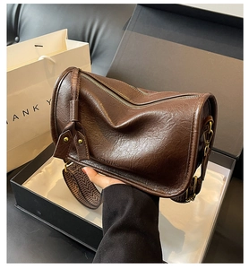 Detail of vintage brown leather saddle bag with dual zippers and patterned strap in gift box