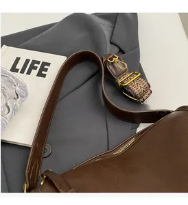 Detail of dark brown saddle bag with ethnic pattern strap and smooth leather handle