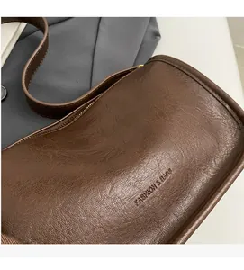 Close-up of brown textured faux leather saddle bag with embossed fashion text and soft finish