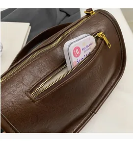 Detail view of brown textured leather saddle bag with side zipper compartment and metal hardware