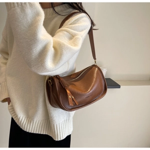 Detail of vintage brown saddle bag showing soft leather texture and tassel accent