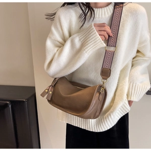 Detail of soft leather saddle bag with geometric patterned wide strap on a white sweater