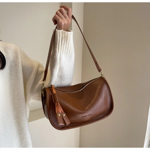Detail der braunen Satteltasche aus Leder mit Quasten und Textur am Modell getragen