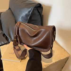 Braune Vintage Satteltasche aus Kunstleder mit gewebtem Gurt auf Steinfläche