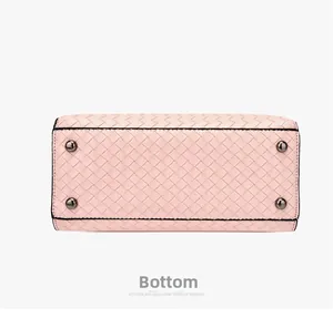 Vue détaillée du fond du sac tissé rose avec rivets en métal et bords noirs laqués