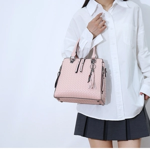 Détail du sac cabas rose tissé avec garnitures argentées et pompon décoratif sur modèle