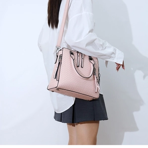 Gros plan sur un sac à main rose à texture tissée avec bandoulière et détail pompon