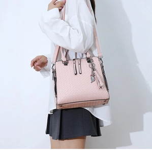 Détail du sac rose à texture tressée avec breloque chat à pompon et pieds en métal