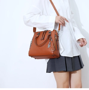 Détail d'un sac cabas marron caramel tissé avec pendentif chat et pompon élégant