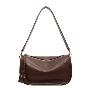 Brown leather saddle shoulder bag with wide strap and decorative tassel in a 45-degree view