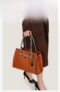 Macro shot of brown tote bag with leopard print scarf handle and silver metal clasp detail