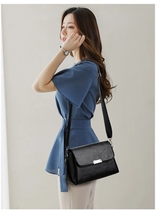 Détail du sac à bandoulière en cuir noir avec boucle argentée et sangle réglable en cuir