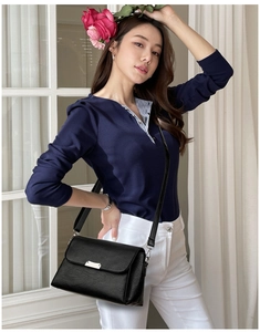 Détail d'un sac bandoulière en cuir noir avec une boucle métallique rectangulaire minimaliste