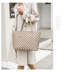 Detail view of beige checkerboard tote bag with adjustable shoulder straps and gold rivets