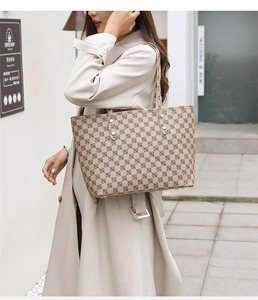 Detail of beige geometric print tote bag with metal rivets and protective bottom feet