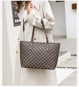 Detailed view of brown checkered pattern on a large tote bag with gold rivets decoration