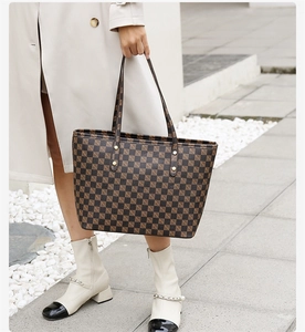 Outdoor shot of a checkerboard tote bag featuring golden studs and dual handles