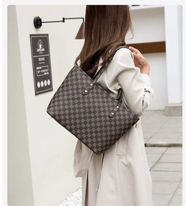 Detailed view of coffee brown checkered tote bag with gold rivets in urban setting