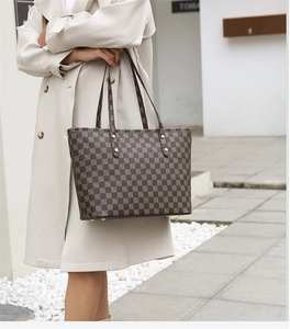 Brown checkerboard tote bag with fine handles shown on a model in a beige trench coat