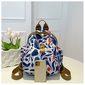 Detail of oxford backpack showing red and blue swirl patterns and gold metal buckle lock