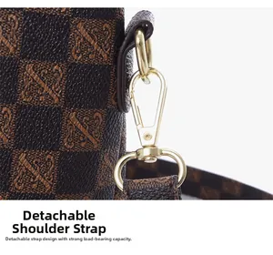 Detail of detachable shoulder strap with golden hardware on brown checkered tote bag