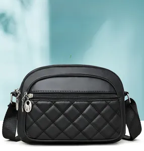 Close-up of black quilted crossbody bag showing three-layer zipper compartments and texture