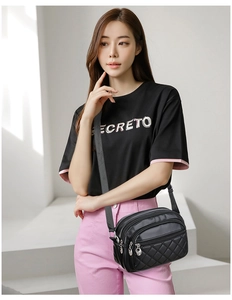 Detail of black quilted crossbody bag with three zipper compartments and wide strap
