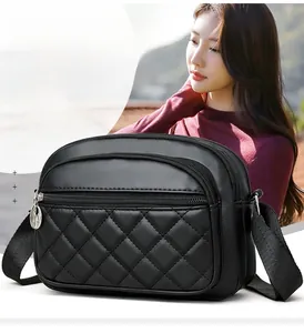 Detail of black quilted leather crossbody bag with multi-zipper layers and woven strap