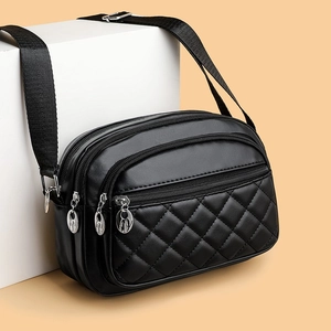 Quilted black square crossbody bag with triple zipper layers and adjustable strap