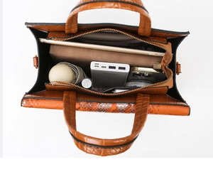 Vista dall'alto dell'interno spazioso della borsa arancione a coccodrillo con accessori