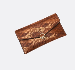 Vista dettagliata della pochette marrone con trama a serpente ed emblema in metallo