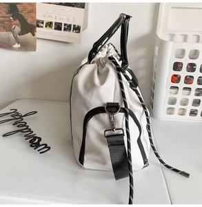 Détail du sac en toile blanche avec poignées en cuir noir et fermeture à cordon