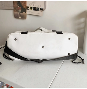 Détail du sac de voyage étanche avec pieds en métal protecteurs sur fond en toile blanche