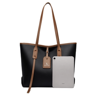 Grande borsa tote minimalista in pelle nera con manici marroni e iPad per scala taglia