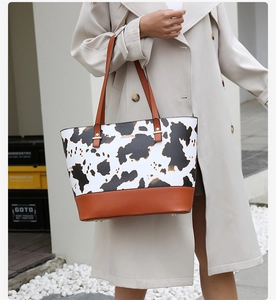 Photo extérieure d'un sac cabas à motif vache avec poignées en cuir et logo