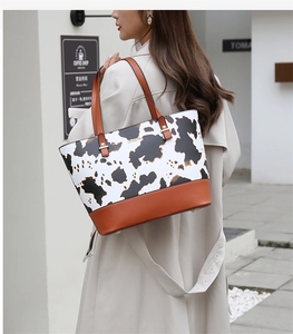 Détail du sac cabas imprimé vache avec anses en cuir marron et logo métallique