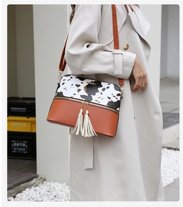 Détail du sac bandoulière en cuir PU à motif vache et marron avec pompons blancs