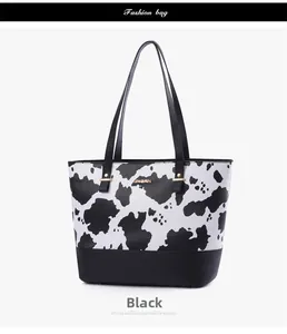 Détail du sac cabas imprimé vache avec logo doré et base en similicuir noir