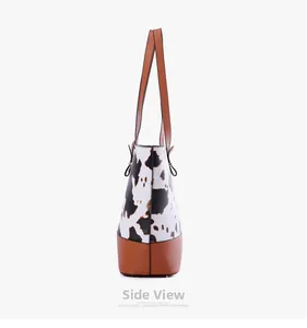 Vue latérale du sac cabas à motif vache avec base en cuir marron et coutures renforcées