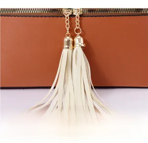 Gros plan sur un sac en cuir marron grainé avec doubles fermetures éclair dorées et pompons