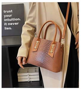 Detail of dark brown crocodile pattern handbag with gold chain accents and shoulder strap