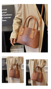 Close-up of brown crocodile embossed handbag featuring golden chain details and leather straps