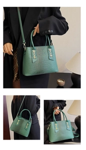 Close-up of emerald green tote with crocodile texture and gold chain link details