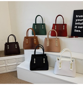Detail of crocodile embossed tote bags in multiple colors with gold chain hardware