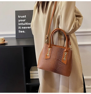 Detail of brown crocodile pattern leather handbag with gold hardware and chain buckle