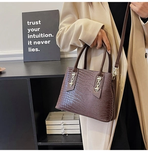 Detail of dark brown crocodile texture tote with gold hardware and top handle