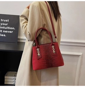 Detail of red crocodile embossed leather tote bag with gold chain and crossbody strap
