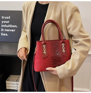 Detail of red crocodile texture handbag with golden chain buckle and luxury hardware